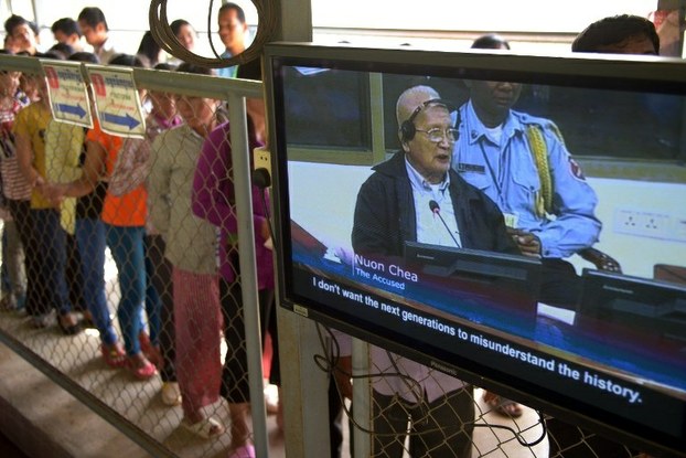 Nuon Chea is seen on a television screen as people line up to attend the trial of former Khmer Rouge leaders at the Extraordinary Chamber in the Courts of Cambodia (ECCC) in Phnom Penh on Oct. 21, 2013.