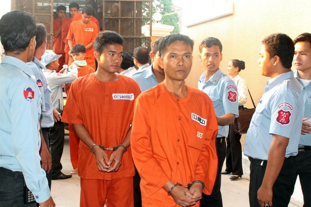 Cambodian rights activists and workers (C) accused of causing violence during a January strike are escorted by prison guards at the Phnom Penh Municipal court, April 25, 2014.