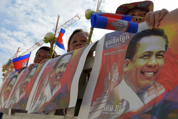 Cambodians hold images of Kem Ley, a Cambodian political analyst who was shot dead in broad daylight on July 10, during a funeral procession for him in Phnom Penh, July 24, 2016.