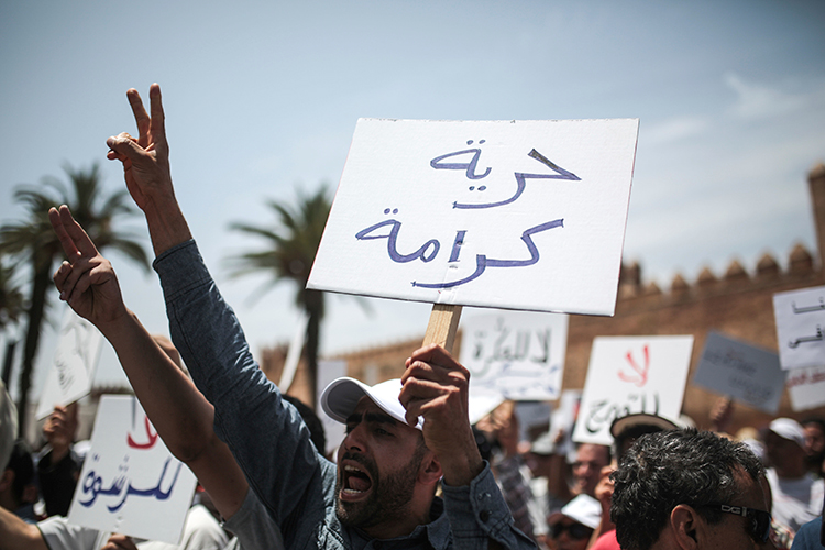 A protester in Rabat holds a sign saying 