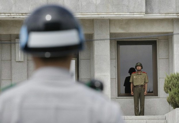 North (R) and South (L) Korean army soldiers stand guard as members at the border village of Panmunjom, that has separated the two Koreas since the Korean War, June 26, 2015