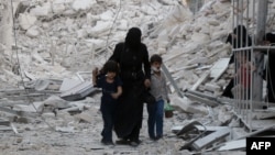 A Syrian family leaves the area following a reported air strike on the Al-Muasalat area in the northern Syrian city of Aleppo on September 23.
