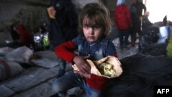 A Syrian girl, who fled with her family from rebel-held areas in the city of Aleppo, carries a sandwich, at a shelter in the neighborhood of Jibrin, east of Aleppo, on November 30.