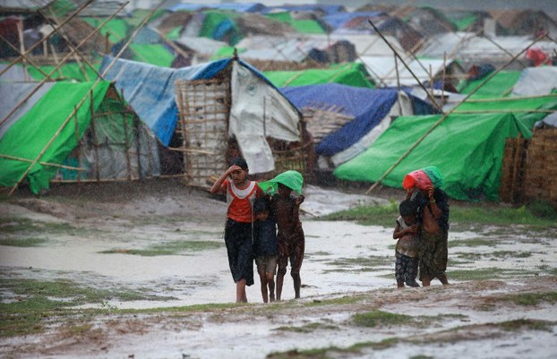 Rohingya children walk in front of their tents as rain falls at a camp for the displaced in Sittwe, May 14, 2013.