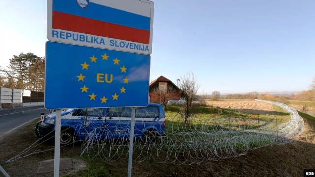 A Slovenian police van is in attendance at a barbed-wire barrier behind a Republic of Slovenia and European Union sign in the village of Rigonce, on Slovenia's border with Croatia on November 12.