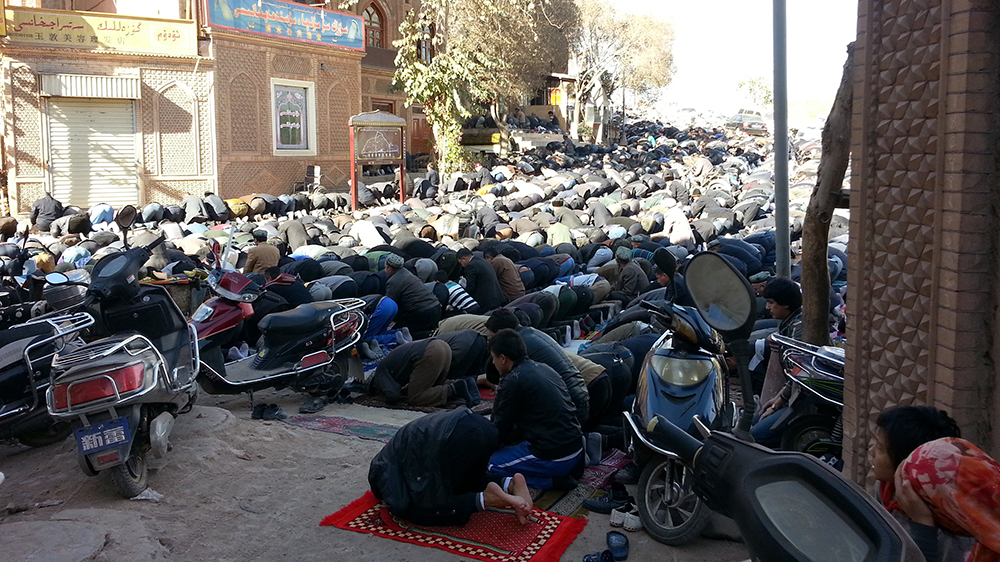 Uyghur men pray on mats outside a mosque in Xinjiang's Kashgar prefecture, in a file photo.