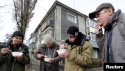 Men eat during a charity event distributing meals for homeless people in Stavropol