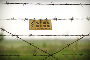 A warning sign is shown on a barbed-wire fence separating China and North Korea, May 27, 2009.