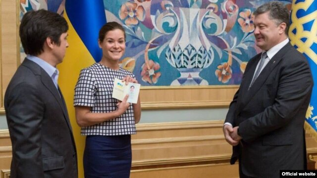 Maria Gaidar (center) holds aloft her newly issued Ukrainian passport, which was presented to her by President Petro Poroshenko (right). Journalist Vladimir Fedorin (left) was also granted Ukrainian citizensjip. 