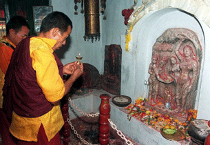 A monk prays before an image of Mayadevi giving birth to the Buddha at Lumbini.