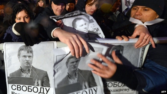 Opposition supporters hold posters bearing portraits of detained opposition activist Leonid Razvozzhayev during a rally in central Moscow on October 30.