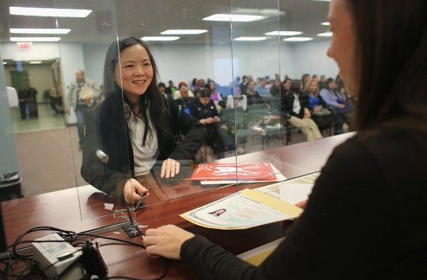 Immigrant from China Joy Bixia smiles after signing a naturalization certificate to become an American citizen at the district office of U.S. Citizenship and Immigration Services in Newark, New Jersey, Jan. 28, 2013.