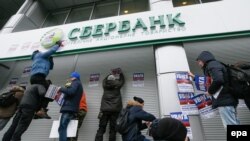 Protesters attach stickers during a protest outside the central branch of Sberbank in Kyiv last month.