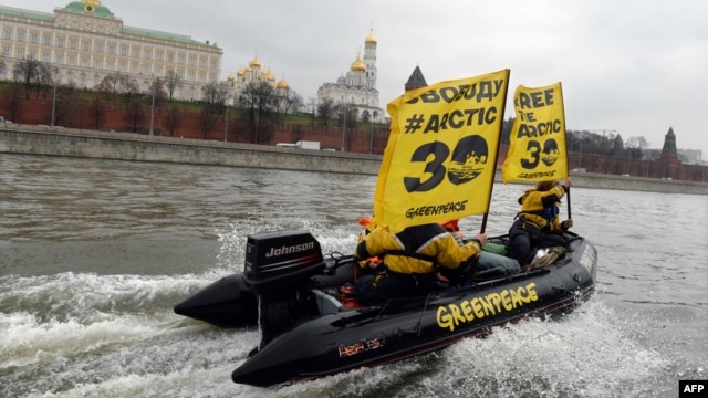 Greenpeace activists hold flags reading 'Free the Arctic 30' as they go past the Kremlin by boat.