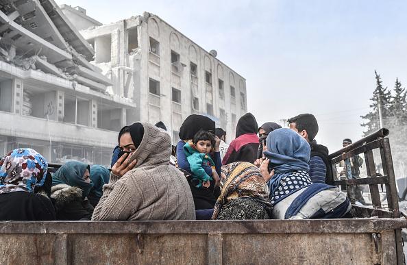 Residents sit in the back of a truck as they flee the city of Afrin in northern Syria on March 18, 2018, after Turkish forces and allied armed groups took control of the Kurdish-majority city.
