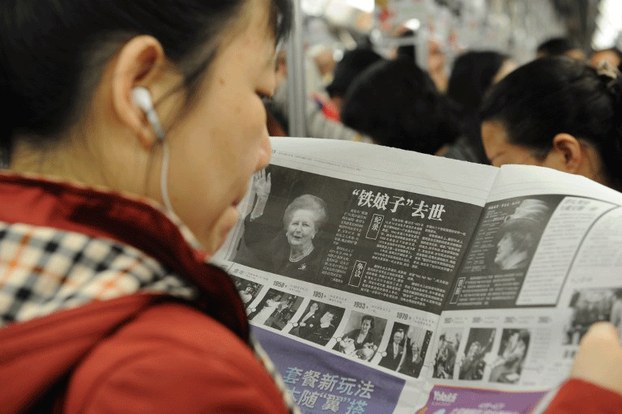 A woman reads about the death of ex-British prime minister Margaret Thatcher in a Chinese newspaper in Shanghai, April 9, 2013.