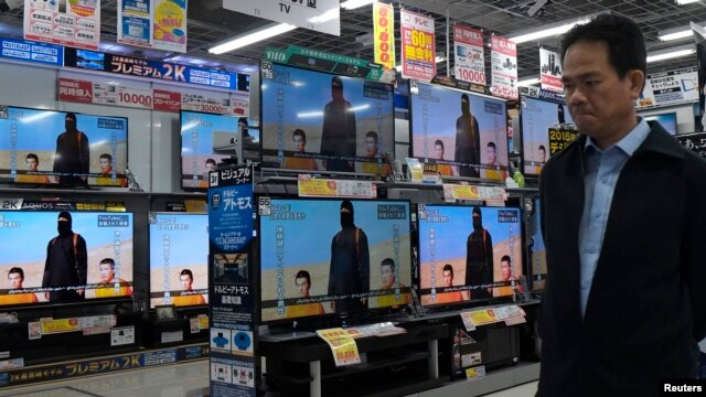 A man walks past televisions sets displaying a news program about an Islamic State video purporting to show two Japanese captives at an electronics store in Tokyo on January 20.