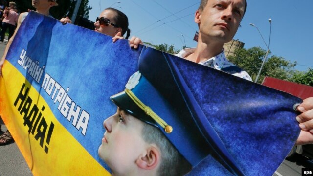 Ukrainian activists hold a banner saying 'Ukraine needs Nadiya' and a Nadiya Savchenko portrait during a rally demanding the release of the Ukrainian officer in front of the Russian Embassy in Kyiv last month.
