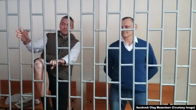 Ukrainian citizens Mykola Karpyuk (right) and Stanislav Klyh (left) in a defendants' cage in a court in Grozny.