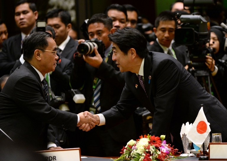 Japanese Prime Minister Shinzo Abe and his Lao counterpart Thongsing Thammavong shake hands at an ASEAN meeting in Brunei, Oct. 9, 2013.