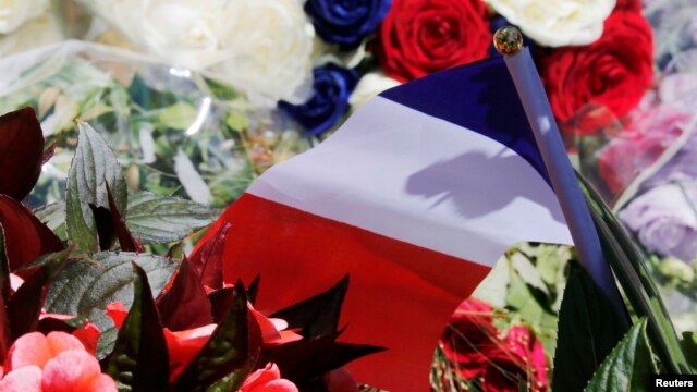 A bouquet of flowers and a French flag are seen as people pay tribute near the scene of the attack in Nice.