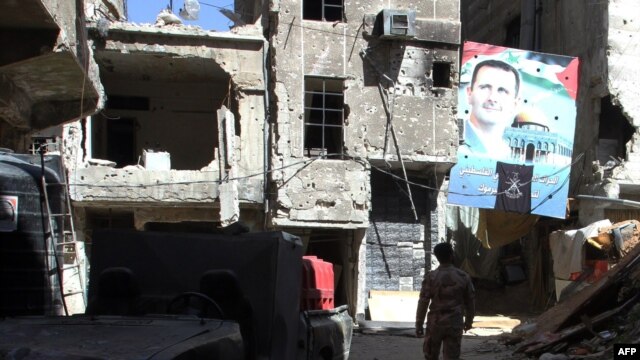 A man walks under a portrait of Syrian President Bashar al-Assad in a street inside the Yarmouk Palestinian refugee camp in the Syrian capital on April 6.