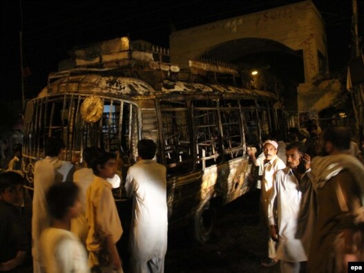 People gather near a bus that was set on fire by a mob in the southern Pakistani port city of Karachi on May 20.