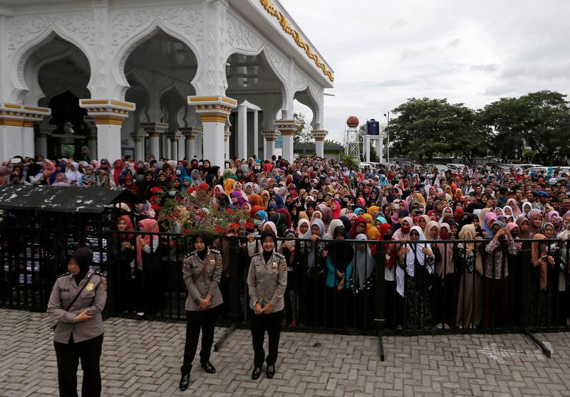 Indonesian police women guard people who watch a man publicly flogged in front of Syuhada mosque in Banda Aceh, Aceh province, Indonesia May 23, 2017.