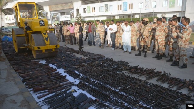 Pakistani paramilitary soldiers watch as a steamroller destroys weapons seized during various search operations against criminal gangs and banned organizations in Karachi on January 6.