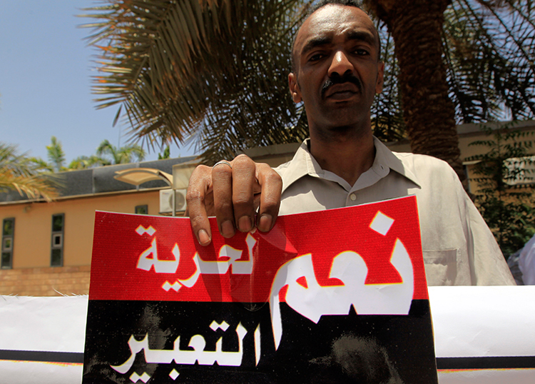 A Sudanese journalist in Khartoum holds a sign reading 