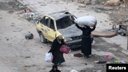 Women carry their belongings as they wait to be evacuated from a rebel-held sector of eastern Aleppo.