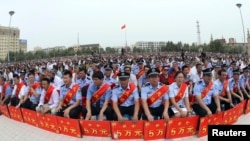 Police wearing sashes hold placards during a ceremony to award those who the authorities say participated in 'the crackdown of violence and terrorists activities' in China's Xinjiang Uyghur Autonomous Region.