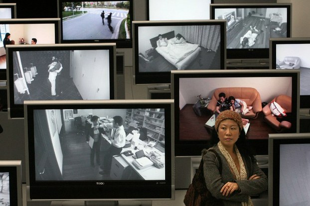 A Chinese woman stands next to videos showing examples of domestic violence at an exhibition in Shanghai, in a file photo