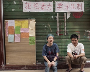 Xiaoxiaocao Workers' Home staff sit outside their shuttered office, Aug. 30, 2012.