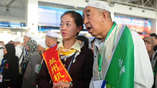 A Chinese Muslim pilgrim is assisted by airport staff in Lanzhou, Gansu Province, as he prepares to travel to Mecca in Saudi Arabia, Sept. 25, 2012.