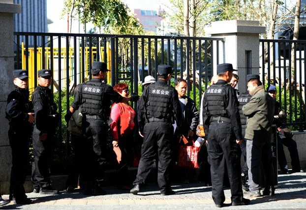 Chinese police ask a group of people who were denied entry to the Urumqi Intermediate People's court to leave as the trial of Ilham Tohti begins in Urumqi, Sept. 17, 2014.