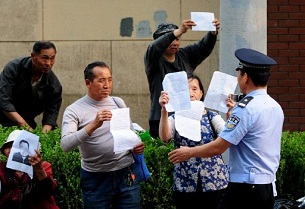 A policeman stops a group of petitioners from demonstrating outside a hospital in Beijing, May 7, 2012.