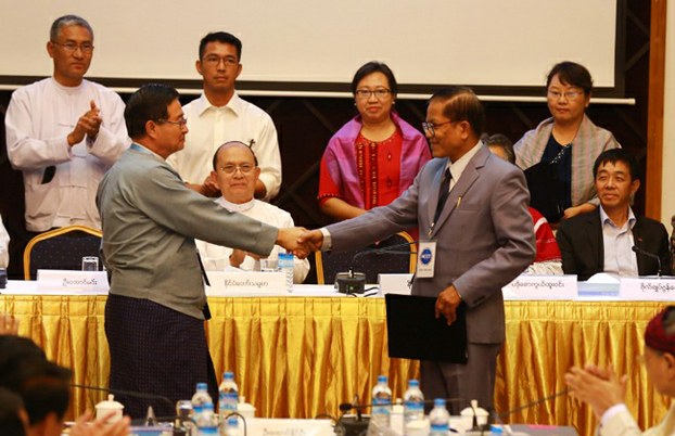 Myanmar President Thein Sein (C) looks on as Aung Min (L), vice chairman of Union Peace Working Committee, shakes hands with Naing Han Tha (R), the leader of the Nationwide Ceasefire Coordinating Team, after they sign a nationwide ceasefire draft agreement in Yangon, March 31, 2015.
