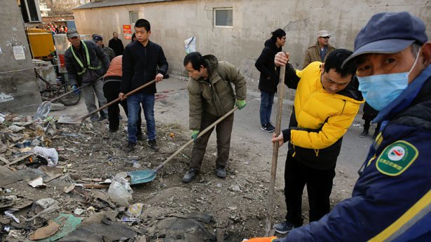 Men shovel debris in Beijing's Baiqiangzi village, which is mainly inhabited by migrant workers, Dec. 13, 2017.