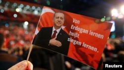 A man holds a flag showing Turkish President Recep Tayyip Erdogan that read's 'Learning from Erdogan means learning how to win' during Prime Minister Binali Yildirim's speech in Oberhausen, Germany, on February 18.