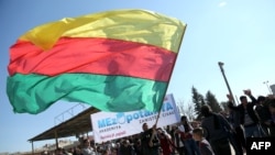 A man waves a flag of the Kurdish People's Protection Units, the military wing of the Democratic Union Party, at a demonstration in the Syrian city of Qamishli on February 4, 2016.