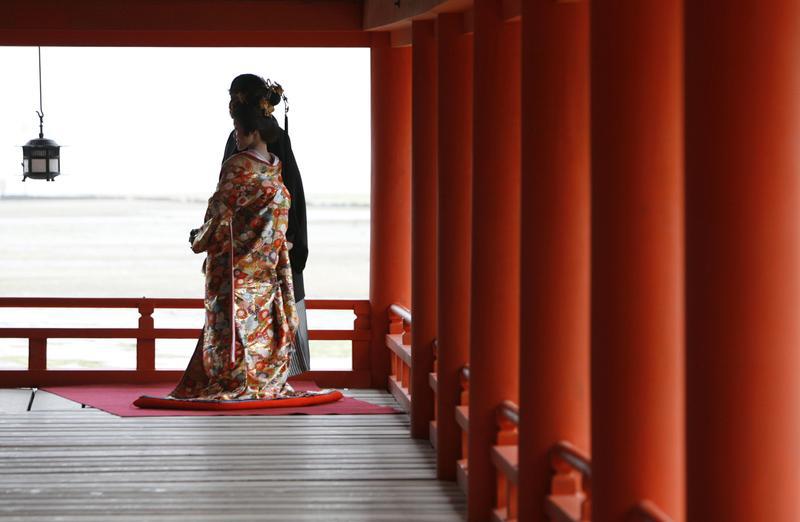 A bride in traditional Japanese wedding attire poses for photos with her groom at the Itsukushima Shrine in Hatsukaichi, southwestern Japan April 16, 2008.