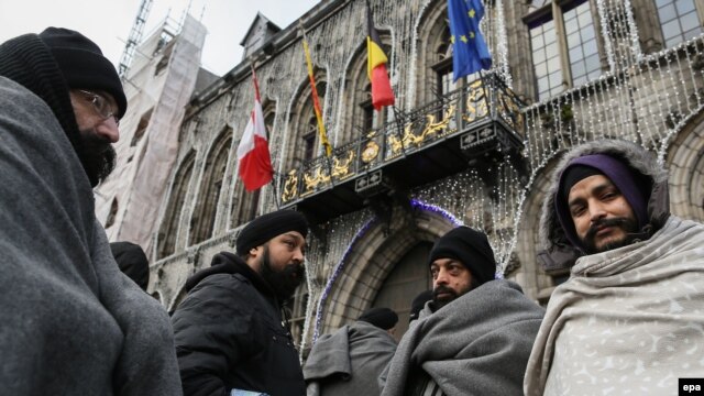 Asylum seekers from Afghanistan wrap themselves in blankets outside the Grand Place in Mons, Belgium, on December 23.
