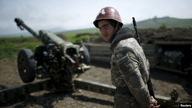 An ethnic Armenian soldier stands next to a cannon at artillery positions near Nagorno-Karabakh's town of Martuni.