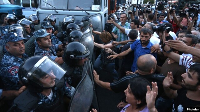 Protesters scuffle with riot police near a police station seized by opposition gunmen in Yerevan on July 19.