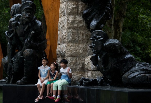 Children pose in front of a sculpture in Shanghai, August 13, 2015.