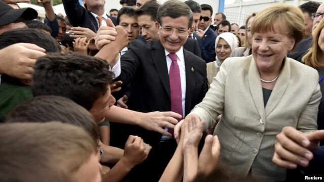 Turkish Prime Minister Ahmet Davutoglu and German Chancellor Angela Merkel greeted by refugees at the Nizip refugee camp on April 23.