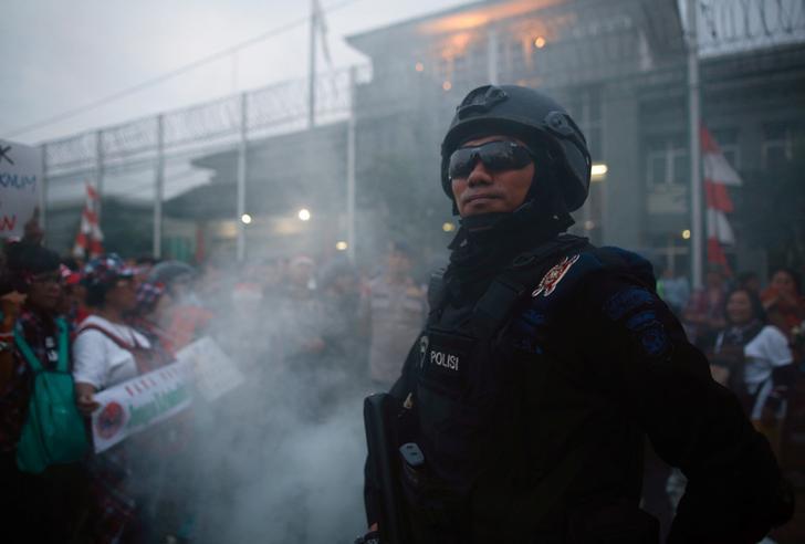 A police officer stands guard during a protest by supporters of Jakarta Governor Basuki Tjahaja Purnama, popularly known as Ahok, outside Cipinang Prison where he was taken following his conviction of blasphemy in Jakarta, Indonesia, 9 May 2017.