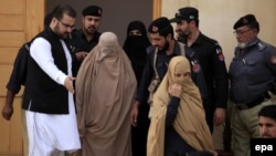 Pakistani security officials escort Sharbat Gula (center, in burqa), after a court hearing in Peshawar on November 4.