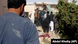 Afghans inspect the site of a suicide attack in Lashkar Gah on October 9.